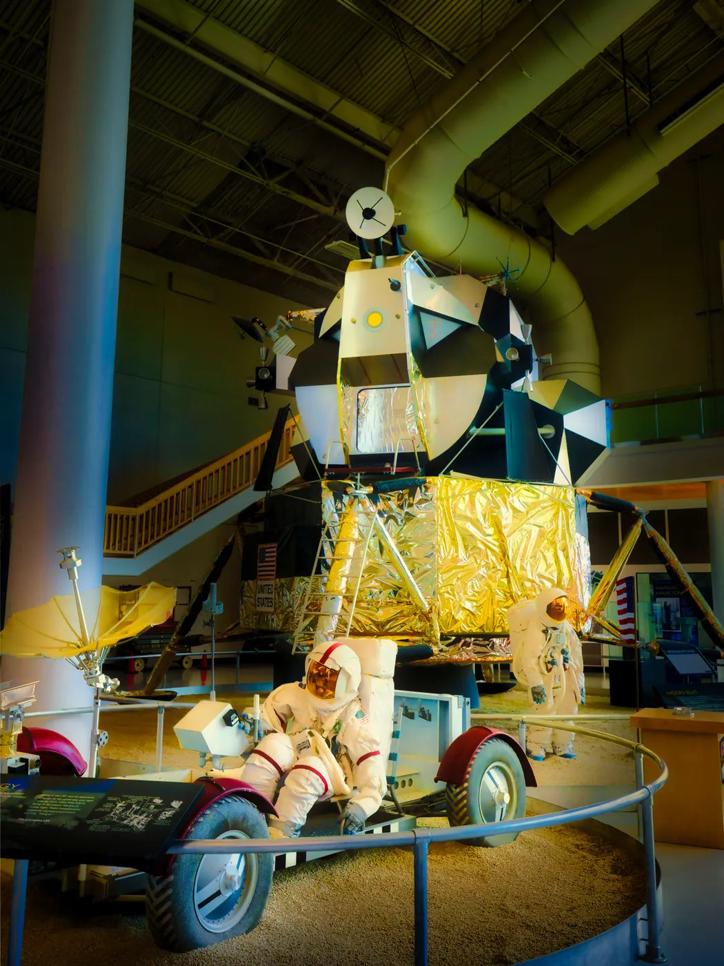 A lunar module, a rover, and a suited figure on simulated regolith
