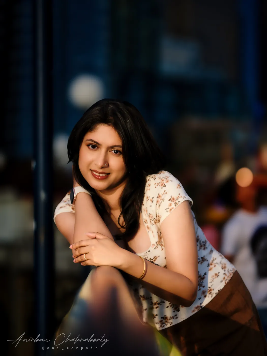 Leaning on a rail while the city goes soft behind her