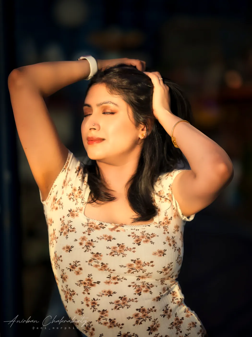 Hands in her hair, low sun across her face